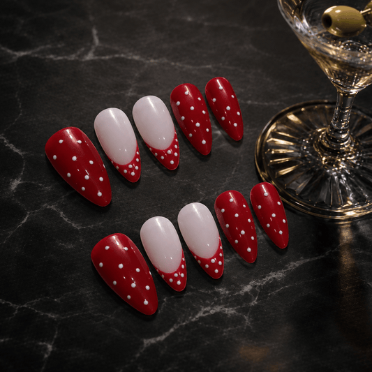 Calm Storm premium red and white polka dot nail art on a dark marble surface with a cocktail glass.