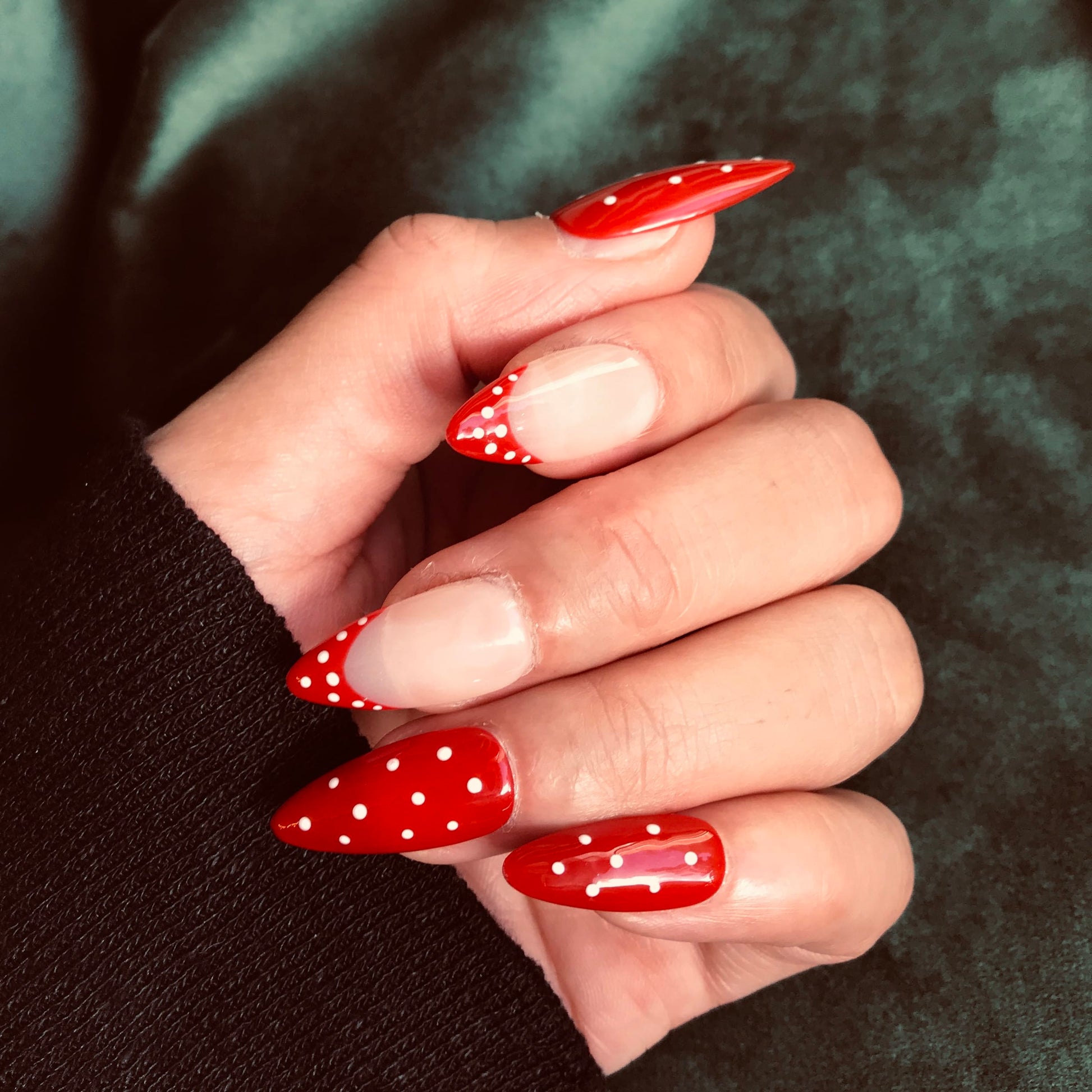 Premium press-on nails in red and white polka design in medium almond. 