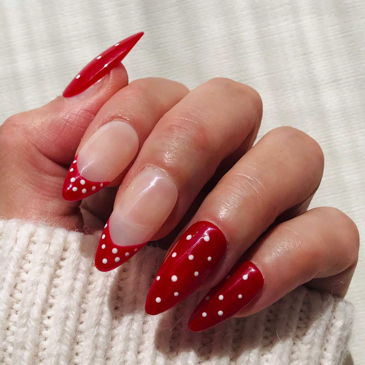 Salon quality press-on nails in red with white polka dot in almond shape. 