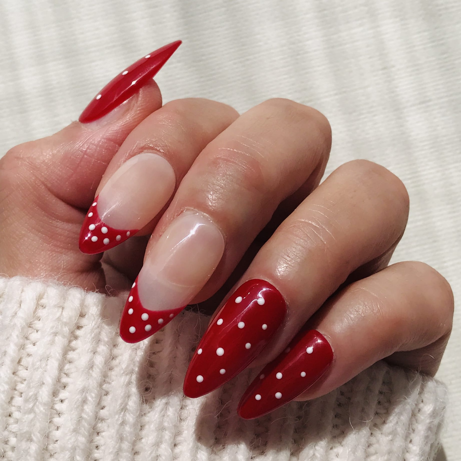 Salon quality press-on nails in red with white polka dot in almond shape. 