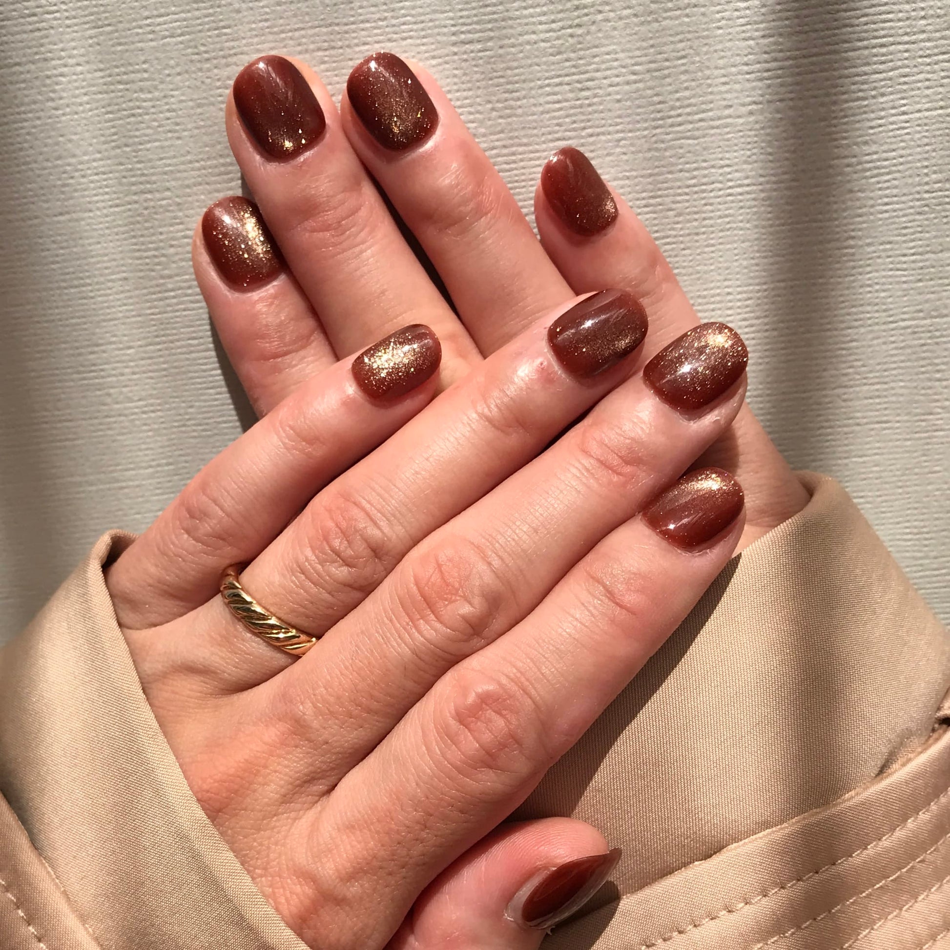 Close-up of hands with glittering caramel press-on nails.