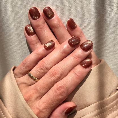 Close-up of hands with glittering caramel press-on nails.
