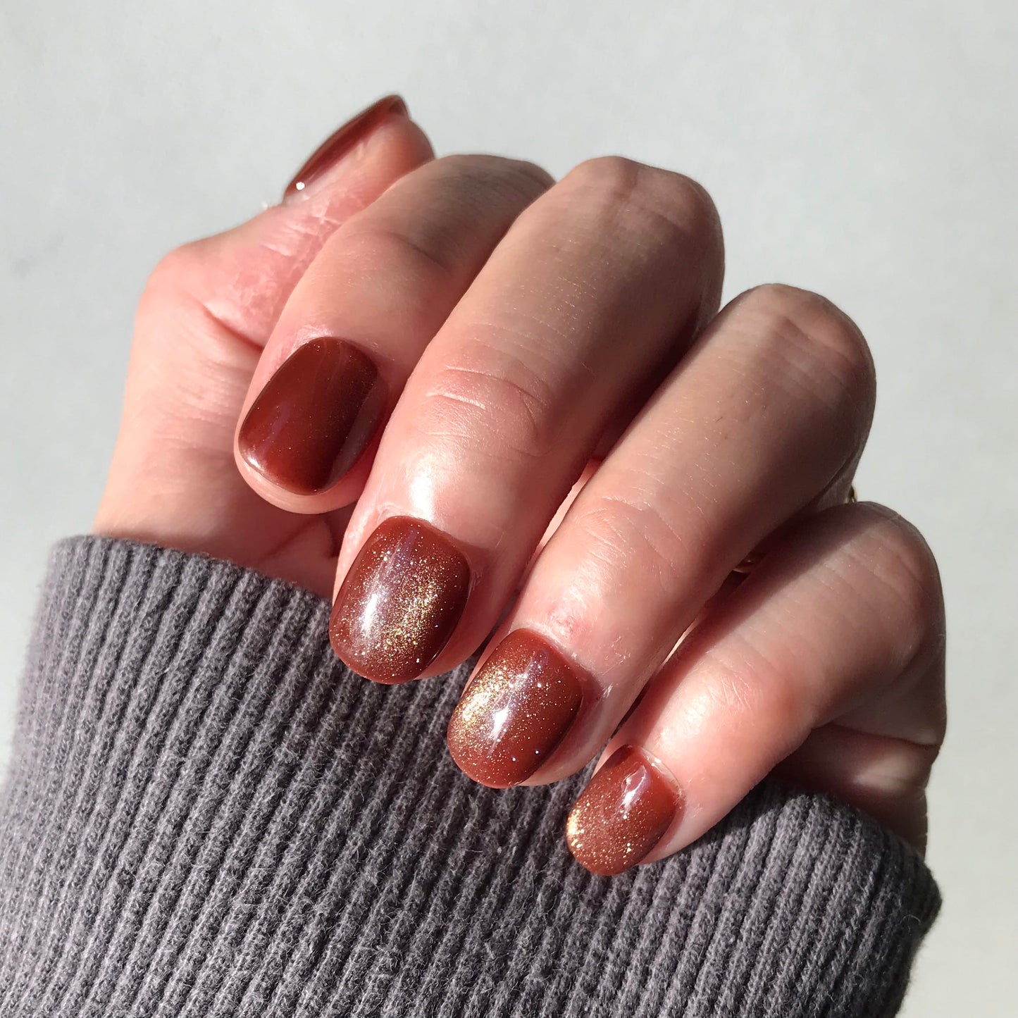 Close-up of a hand with rich glittering caramel press-on nails.
