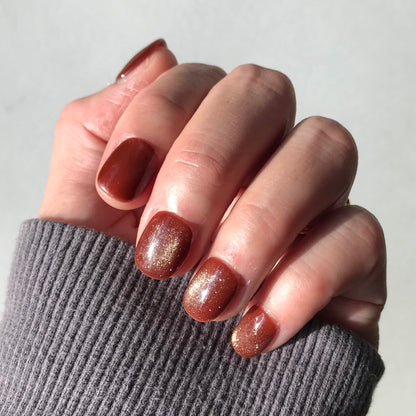 Close-up of a hand with rich glittering caramel press-on nails.