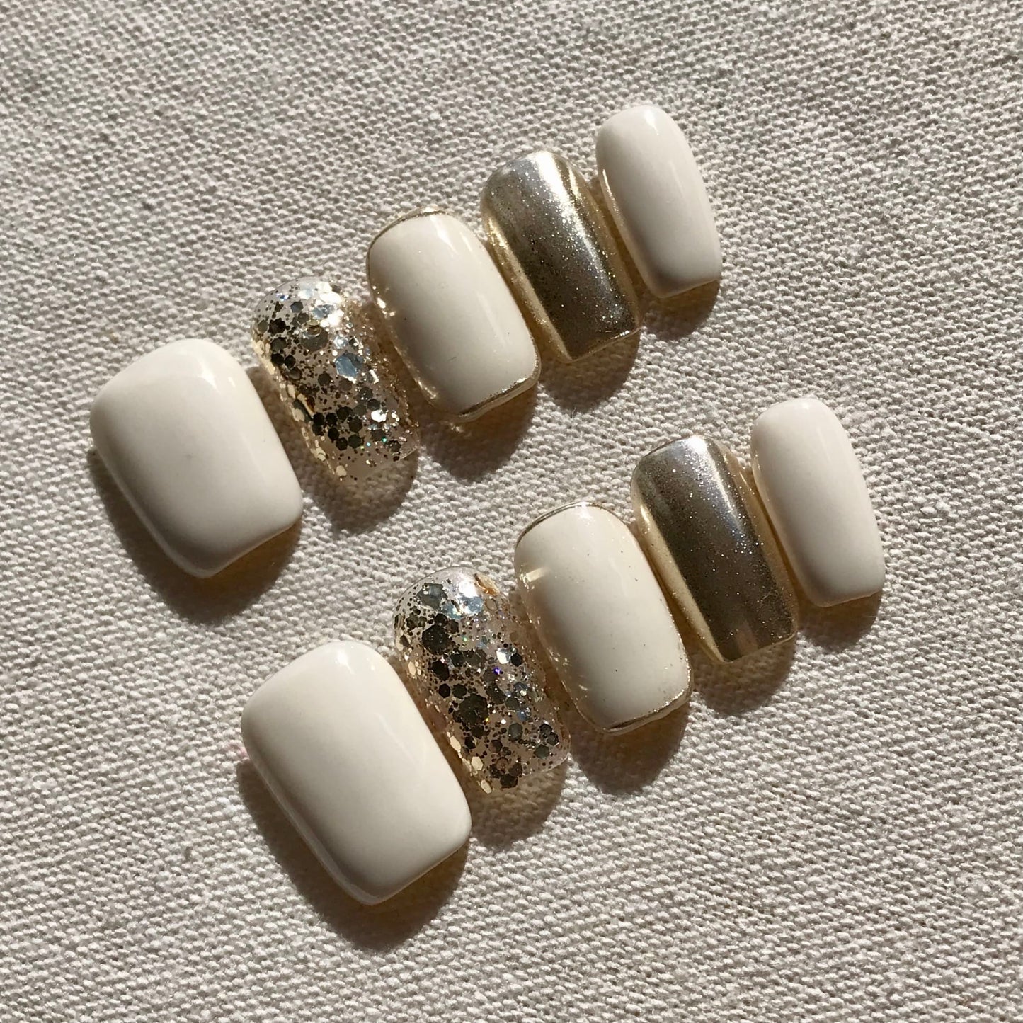 Calm Storm premium handmade press-on nails in white and gold with gold glitter detail.