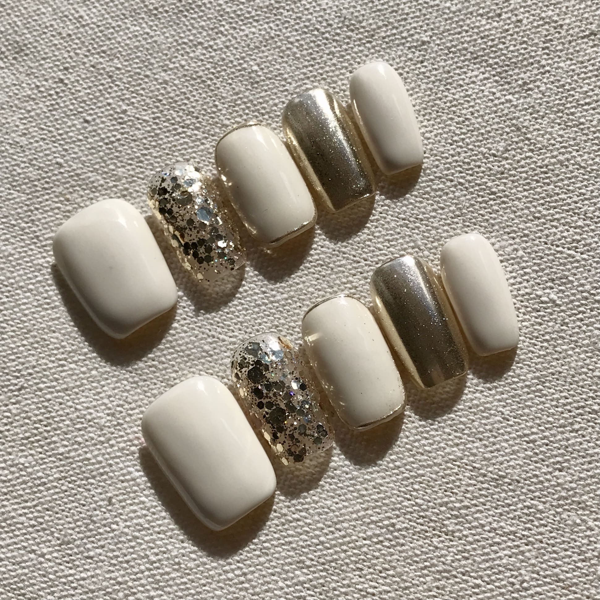 Calm Storm premium handmade press-on nails in white and gold with gold glitter detail.