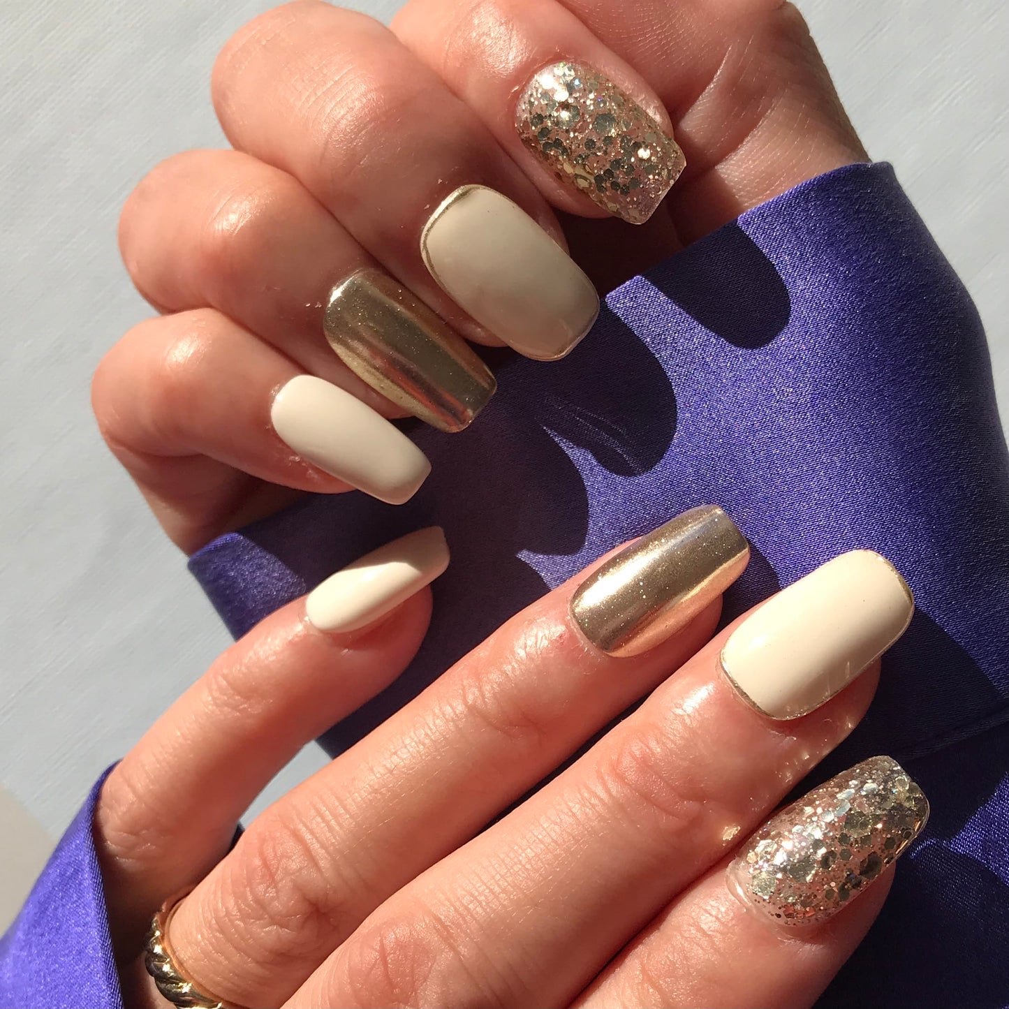 Close-up of hands with white and gold press-on nails in medium square shape.