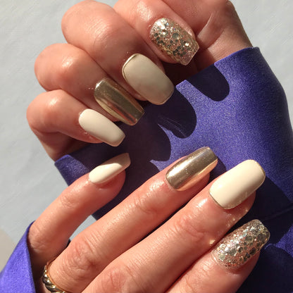 Close-up of hands with white and gold press-on nails in medium square shape.