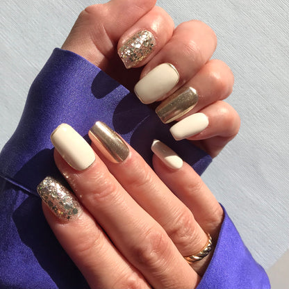 Hands modelling premium press-on nails in white, gold with gold glitter design.