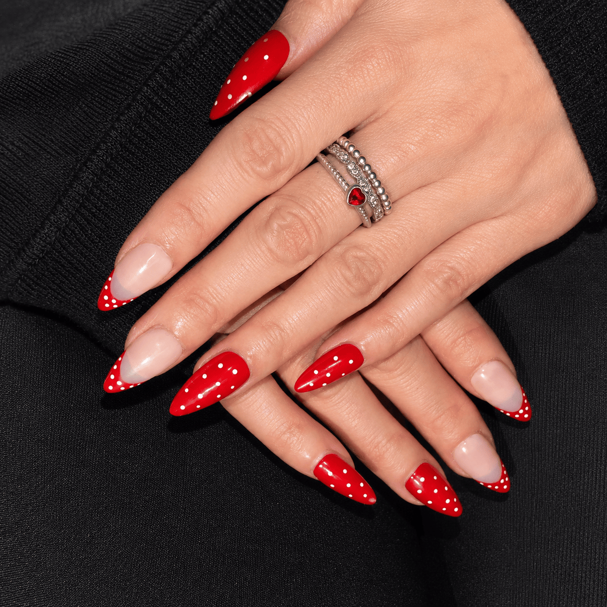 A close-up of hands wearing a red and white polka dot press-on nails.